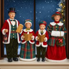 Victorian Christmas carol singing family figurines standing on a windowsill, dressed in festive plaid outfits with songbooks, in front of a snowy night backdrop.