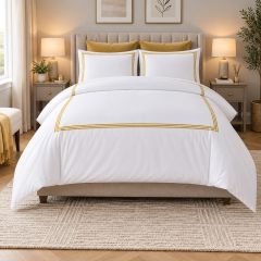 White duvet cover set with elegant gold border detailing, styled on a bed in a modern luxury bedroom.