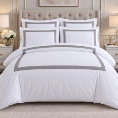 White luxury duvet cover set with elegant grey border detailing and matching pillowcases, shown from the front in a modern bedroom