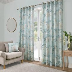 Duck egg curtains with a soft wisteria floral print and matching cushion in a bright living room.