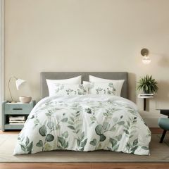White comforter set with a soft green leafy print, styled on a bed in a modern bedroom.